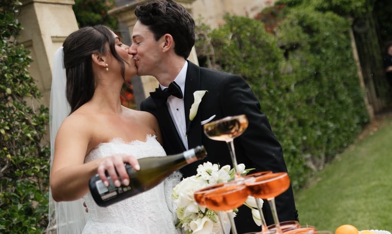 Bride and groom kissing while celebrating with champagne in a garden setting